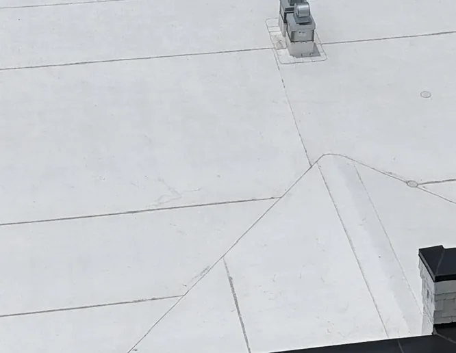 High-angle aerial view of a white commercial flat roof installed on The Suites at Americana building by Blancos Roofing in Baton Rouge, LA.